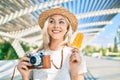 Young caucasian tourist girl using vintage camera and eating ice cream at street of city Royalty Free Stock Photo