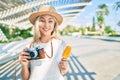 Young caucasian tourist girl using vintage camera and eating ice cream at street of city Royalty Free Stock Photo