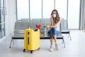 Young Caucasian traveler female wear mask for prevention for covid-19 virus is sitting on waiting chairs for passengers in the