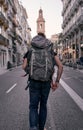 young caucasian traveler man running along the asphalt of a city street with a backpack on his back, valencia, spain Royalty Free Stock Photo