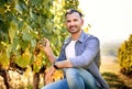 Young caucasian vintner checking the grapes  on the vineyard before harvesting and smiling into the camera - Wine making and Royalty Free Stock Photo