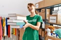 Young caucasian volunteer woman smiling happy holding books at charity center