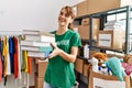 Young caucasian volunteer woman smiling happy holding books at charity center