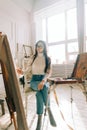 Young caucasian woman artist holding paintbrush and draws on canvas working on a home studio Royalty Free Stock Photo