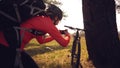 Young caucasian woman athlete tourist cyclist makes photo on phone, photographs his bike standing near tree on nature