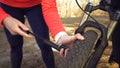 Young caucasian woman athlete tourist cyclist uses a hand tool, a bicycle pump to inflate air into a tire wheel mountain bike. Royalty Free Stock Photo