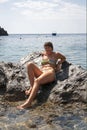 Beautiful girl lying down on a rock in the sea. Relax.