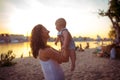 Young Caucasian woman, beautiful mother holds a child in her arms, mom hugs her one-year-old son standing on a sandy beach in a Royalty Free Stock Photo