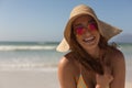 Young Caucasian woman in bikini with hat and sunglasses looking at camera on the beach Royalty Free Stock Photo