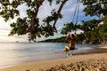 Young caucasian woman in bikini swinging on wooden swing hanging from the tree on Anse Lazio beach, Seychelles. Royalty Free Stock Photo