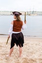 Young Caucasian woman in black and brown pirate costume raised toy gun