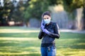 Young Caucasian woman in black leather jacket and surgical mask takes on purple latex gloves Royalty Free Stock Photo