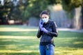 Young Caucasian woman in black leather jacket and surgical mask takes on purple latex gloves Royalty Free Stock Photo