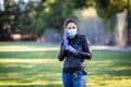 Young Caucasian woman in black leather jacket and surgical mask takes on purple latex gloves Royalty Free Stock Photo