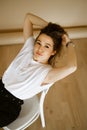 young caucasian woman in black pants and a white T-shirt sitting on a chair, portrait of a brown-eyed brunette with