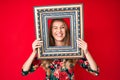 Young caucasian woman with blond hair holding empty frame winking looking at the camera with sexy expression, cheerful and happy Royalty Free Stock Photo