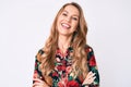 Young caucasian woman with blond hair wearing elegant floral shirt happy face smiling with crossed arms looking at the camera