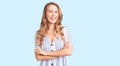 Young caucasian woman with blond hair wearing summer dress happy face smiling with crossed arms looking at the camera Royalty Free Stock Photo