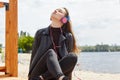 Young caucasian woman in blue red headphones listens to music on the river bank with a digital tablet Royalty Free Stock Photo