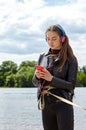 Young caucasian woman in blue red headphones listens to music and typing on the smartphone on the river bank. Royalty Free Stock Photo