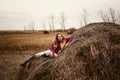 Young Caucasian woman in boots lying on a haystack in a field, cloudy day Royalty Free Stock Photo