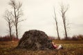 Young Caucasian woman in boots lying near a haystack in a field