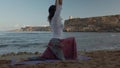 Young caucasian woman, brunette doing yoga on the beach in the early autumn morning