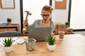 Young caucasian woman business worker stressed breaking laptop with hammer at office Royalty Free Stock Photo