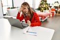 Young caucasian woman call center agent stressed teleworking sitting by christmas tree at home Royalty Free Stock Photo