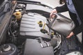 Young Caucasian woman checking the car`s engine oil. Car maintenance concept Royalty Free Stock Photo