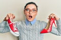 Young caucasian woman choosing high heel shoes and sneakers afraid and shocked with surprise and amazed expression, fear and