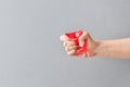 Young caucasian woman crashing in clenched hand fist red single use cup on gray wall background. Zero waste plastic free Royalty Free Stock Photo