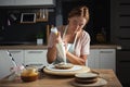 Young caucasian woman decorating cake with professional tools. Confectioner in the modern stylish kitchen