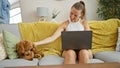 Young caucasian woman with dog smiling using laptop sitting on the sofa at home Royalty Free Stock Photo