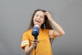 Young caucasian woman dries hair with a hairdryer on a gray background, has fun, sings like a microphone Royalty Free Stock Photo