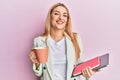 Young caucasian woman drinking a cup of coffee and holding laptop smiling with a happy and cool smile on face Royalty Free Stock Photo