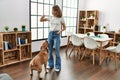 Young caucasian woman feeding dog standing at home Royalty Free Stock Photo