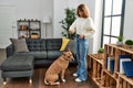 Young caucasian woman feeding dog standing at home Royalty Free Stock Photo