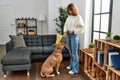 Young caucasian woman feeding dog standing at home Royalty Free Stock Photo