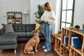 Young caucasian woman feeding dog standing at home Royalty Free Stock Photo