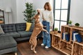 Young caucasian woman feeding dog standing at home Royalty Free Stock Photo