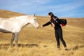 Young woman feeding a wild white horse on a meadow Royalty Free Stock Photo