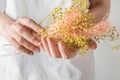 Young caucasian woman florist holds in hands bouquet of dry pink yellow decorative autumn flowers white wall background. Botanical Royalty Free Stock Photo