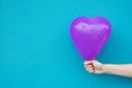 Young Caucasian Woman Girl Holds in Hand Purple Heart Shaped Air Balloon on Turquoise Painted Wall Background. Love Charity