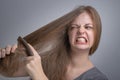 Young caucasian woman girl struggling to comb brush her straight hair with funny frustrated face. Long hair problem concept Royalty Free Stock Photo