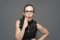 Young caucasian woman in glasses holds hands on the head posing on a gray background. Royalty Free Stock Photo