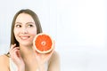 Young Caucasian woman with half of grapefruit in her hand, biting her lips. Studio portrait  on white background Royalty Free Stock Photo