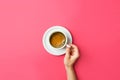 Young caucasian woman hands holds white cup with freshly brewed coffee with foamy crema on saucer on gradient fuchsia pink