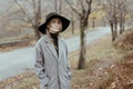 Young caucasian woman in a hat and a gray coat in the rain against the backdrop of an autumn landscape. Royalty Free Stock Photo