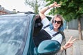 Young caucasian woman with her body out of the window car looking at camera and smiling with two finger making victory sign Royalty Free Stock Photo